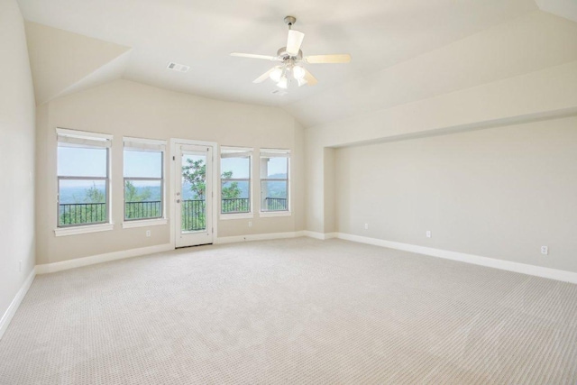 spare room with light colored carpet, vaulted ceiling, visible vents, and baseboards