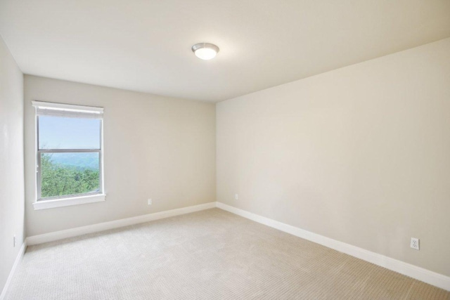 spare room featuring baseboards and light carpet