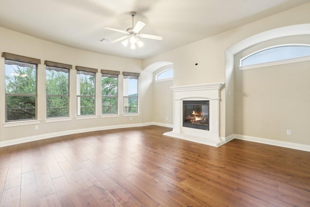 unfurnished living room with hardwood / wood-style flooring, baseboards, a ceiling fan, and a glass covered fireplace