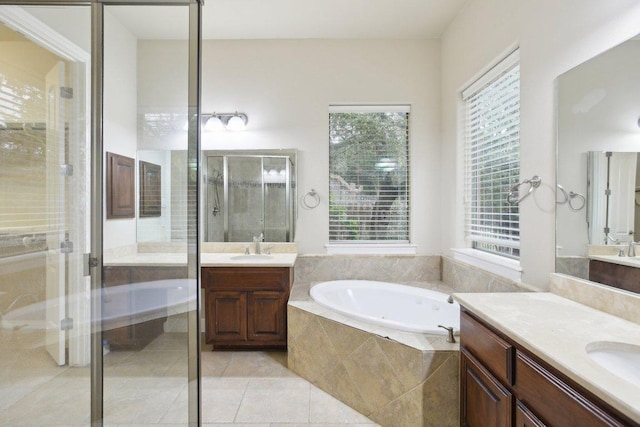 full bath featuring a bath, tile patterned flooring, two vanities, and a stall shower