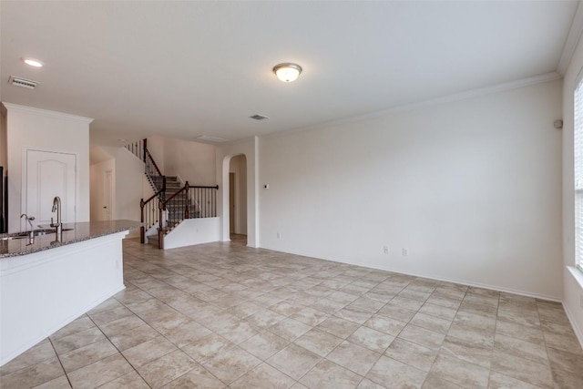 339 Alamosa Dr, Georgetown, TX 78626 - unfurnished living room featuring arched walkways, stairs, and crown molding