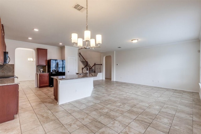 339 Alamosa Dr, Georgetown, TX 78626 - kitchen featuring arched walkways, stainless steel microwave, black refrigerator with ice dispenser, ornamental molding, and backsplash