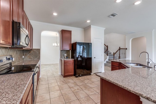 339 Alamosa Dr, Georgetown, TX 78626 - kitchen with range with electric stovetop, black fridge with ice dispenser, arched walkways, light tile patterned floors, and tasteful backsplash