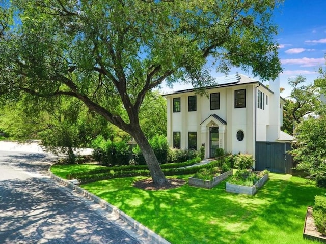 2000 Raleigh Ave, Austin, TX 78703 - view of front of property with roof mounted solar panels, a front lawn, a vegetable garden, and stucco siding