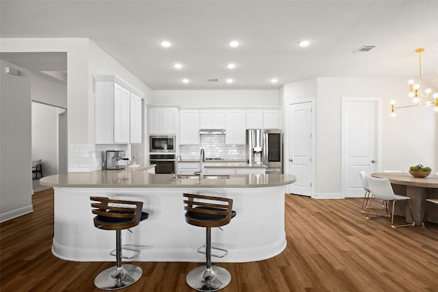 124 Adina Dr, Dripping Springs, TX 78620 - kitchen with stainless steel appliances, a sink, a peninsula, white cabinetry, and tasteful backsplash