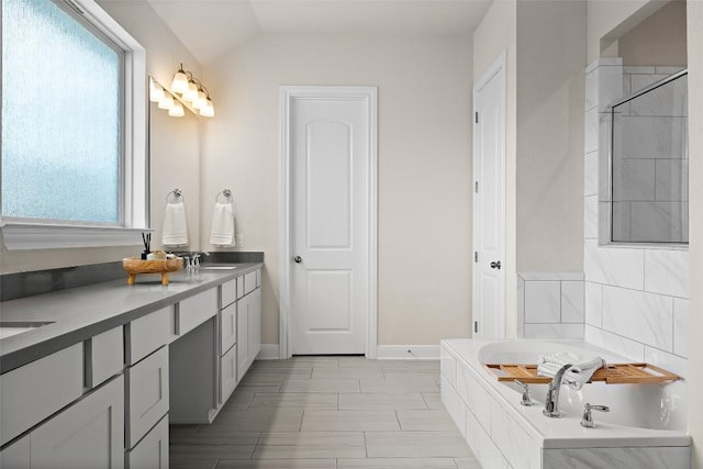 124 Adina Dr, Dripping Springs, TX 78620 - full bath with plenty of natural light, a garden tub, double vanity, lofted ceiling, and baseboards