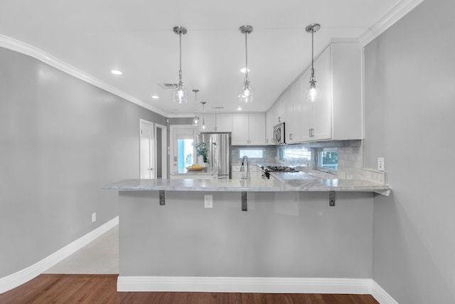 1308 Kinney Ave, Austin, TX 78704 - kitchen featuring stainless steel appliances, a peninsula, light stone countertops, white cabinetry, and backsplash
