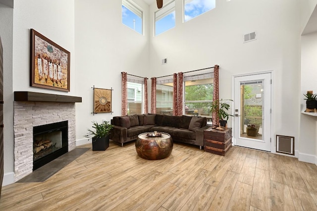 living area with a towering ceiling, wood finished floors, a fireplace, and baseboards
