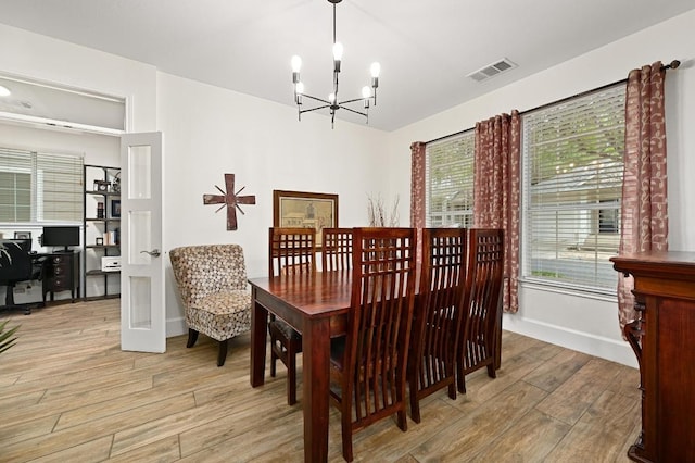 dining room with a chandelier, light wood-type flooring, a desk, baseboards, and vaulted ceiling