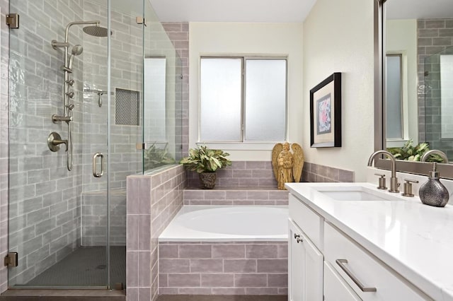 full bathroom featuring a shower stall, a garden tub, and vanity
