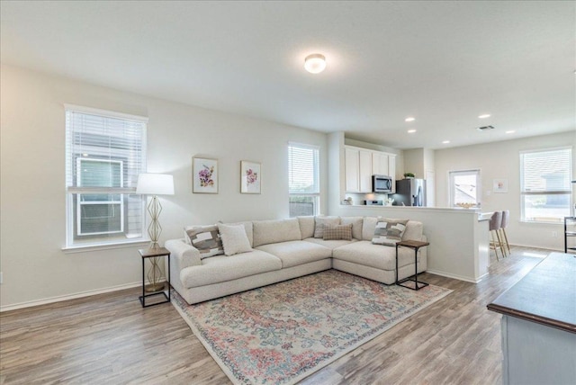 living room featuring healthy amount of natural light, light wood-style flooring, baseboards, and recessed lighting