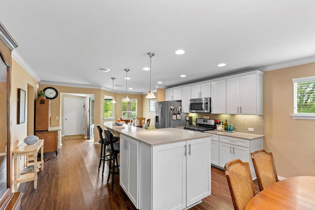 308 Hobby St, Georgetown, TX 78633 - kitchen with appliances with stainless steel finishes, dark wood-type flooring, white cabinets, a center island, and ornamental molding