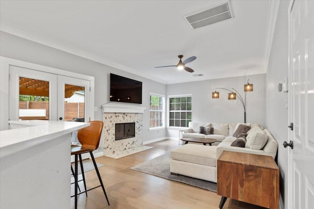 6301 Harrogate Dr, Austin, TX 78759 - living room featuring crown molding, ceiling fan, light wood-style flooring, a tile fireplace, and french doors