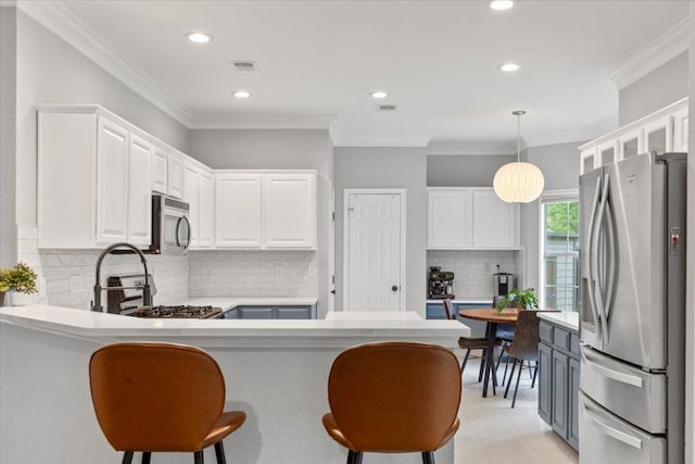 6301 Harrogate Dr, Austin, TX 78759 - kitchen with stainless steel appliances, a peninsula, white cabinetry, light countertops, and ornamental molding