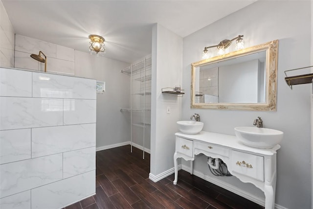 11708 Hornsby Dr, Austin, TX 78753 - bathroom featuring double vanity, wood finished floors, baseboards, and tiled shower
