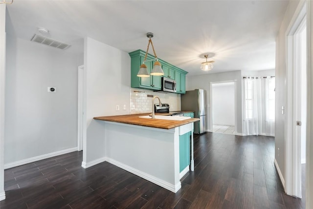 11708 Hornsby Dr, Austin, TX 78753 - kitchen featuring green cabinetry, stainless steel appliances, wood counters, and baseboards