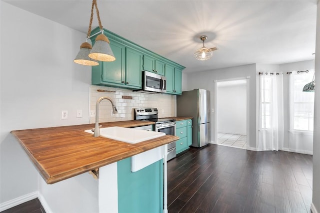 11708 Hornsby Dr, Austin, TX 78753 - kitchen with appliances with stainless steel finishes, green cabinets, a peninsula, backsplash, and baseboards