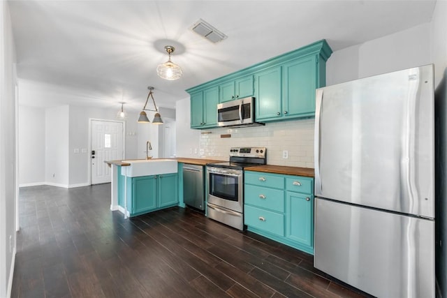 11708 Hornsby Dr, Austin, TX 78753 - kitchen featuring stainless steel appliances, a peninsula, wood counters, decorative backsplash, and dark wood-style flooring