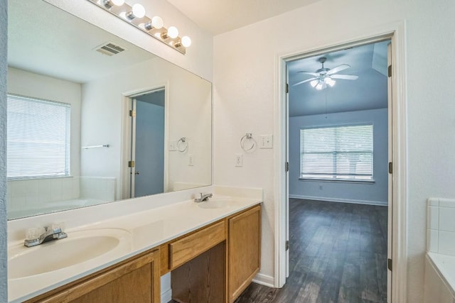 211 Warner Bnd, Hutto, TX 78634 - full bathroom with double vanity, wood finished floors, a bath, and a ceiling fan