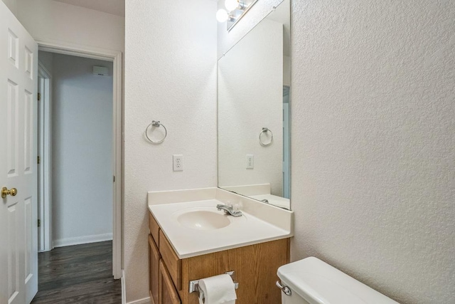 211 Warner Bnd, Hutto, TX 78634 - half bath with vanity, toilet, wood finished floors, a textured wall, and baseboards
