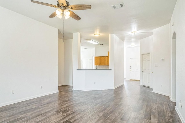 211 Warner Bnd, Hutto, TX 78634 - unfurnished living room featuring arched walkways, dark wood finished floors, a ceiling fan, and baseboards