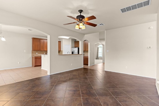 5405 English Oak Dr, Killeen, TX 76542 - unfurnished living room with dark tile patterned flooring, ceiling fan, visible vents, and arched walkways