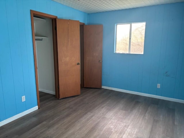 1008 W Pietzsch St, Bartlett, TX 76511 - unfurnished bedroom with wood finished floors, baseboards, a closet, and wooden walls