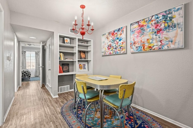 2425 Ashdale Dr Unit 78, Austin, TX 78757 - dining area with a notable chandelier, visible vents, baseboards, and wood finished floors