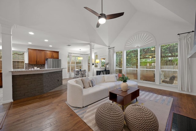 living room with high vaulted ceiling, light wood finished floors, ornate columns, and a ceiling fan
