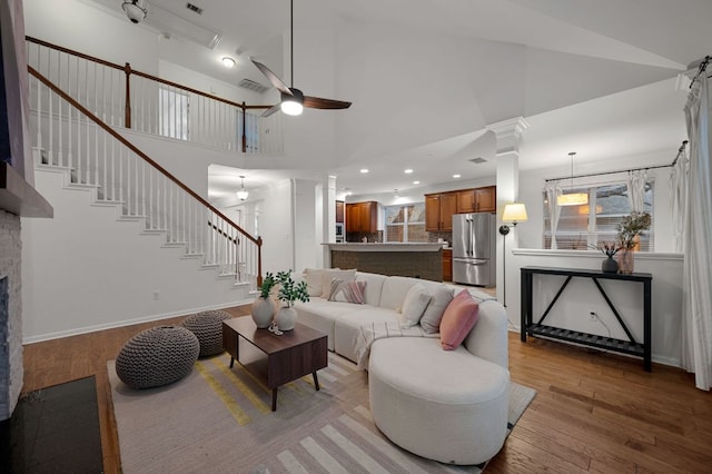 living room with wood finished floors, a ceiling fan, a fireplace, stairway, and visible vents