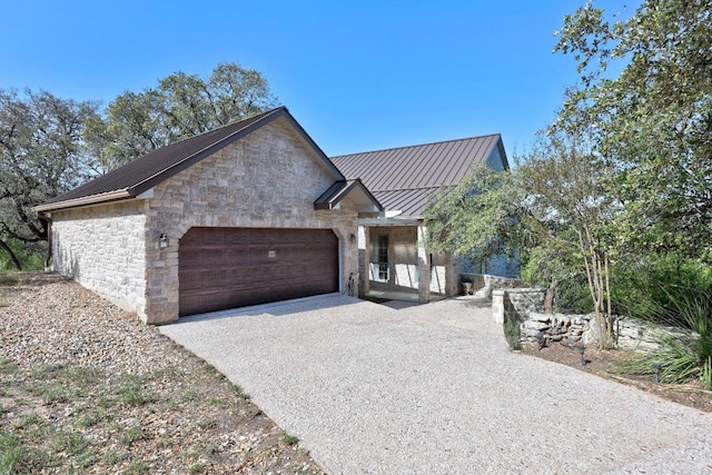 515 Coventry Rd, Spicewood, TX 78669 - view of front of property with a metal roof, stone siding, an attached garage, a standing seam roof, and concrete driveway