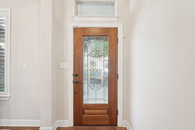 doorway to outside with baseboards and wood finished floors