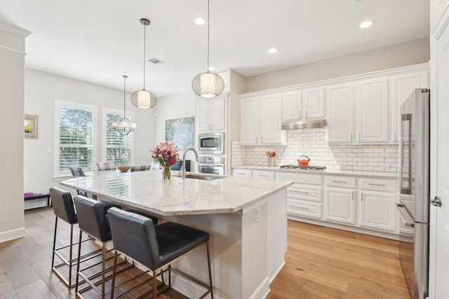 kitchen featuring stainless steel appliances, white cabinetry, backsplash, under cabinet range hood, and visible vents