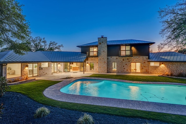 9909 Oliver Dr, Austin, TX 78736 - rear view of house with a standing seam roof, a metal roof, a balcony, a patio, and a chimney