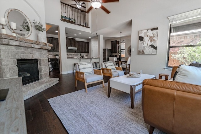 121 E Adelanta Pl, Round Rock, TX 78681 - living room featuring a ceiling fan, dark wood-type flooring, a fireplace, baseboards, and a towering ceiling