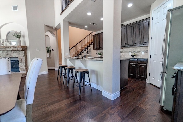 121 E Adelanta Pl, Round Rock, TX 78681 - kitchen with freestanding refrigerator, dark wood-style flooring, a breakfast bar area, dark brown cabinets, and recessed lighting