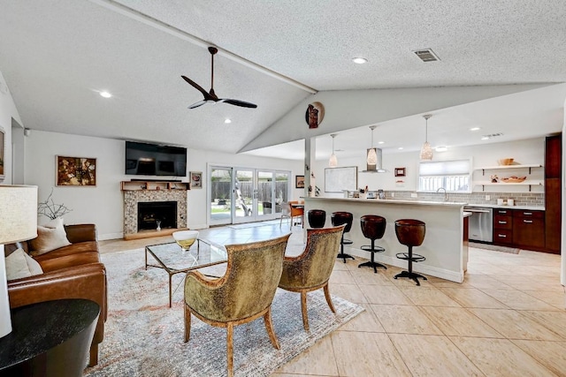 6567 Fair Valley Trl, Austin, TX 78749 - living room featuring a ceiling fan, healthy amount of natural light, a fireplace with raised hearth, vaulted ceiling, and light tile patterned flooring