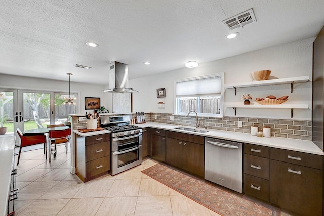 6567 Fair Valley Trl, Austin, TX 78749 - kitchen featuring appliances with stainless steel finishes, wall chimney range hood, light countertops, dark brown cabinetry, and backsplash