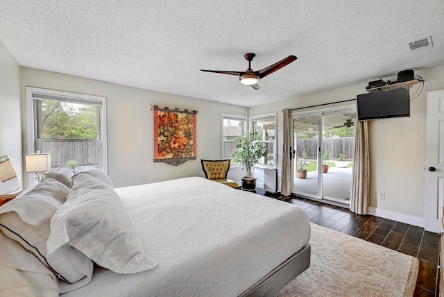 6567 Fair Valley Trl, Austin, TX 78749 - bedroom featuring access to outside, multiple windows, dark wood-style flooring, a textured ceiling, and a ceiling fan