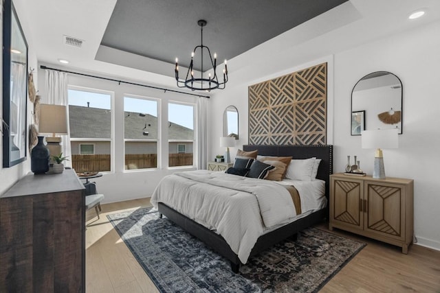 13615 Thomas Wheeler Way, Manor, TX 78653 - bedroom with a chandelier, light wood-style flooring, a raised ceiling, and recessed lighting