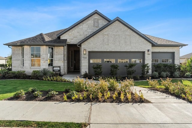 13615 Thomas Wheeler Way, Manor, TX 78653 - french country style house featuring an attached garage, a front lawn, a shingled roof, and stone siding