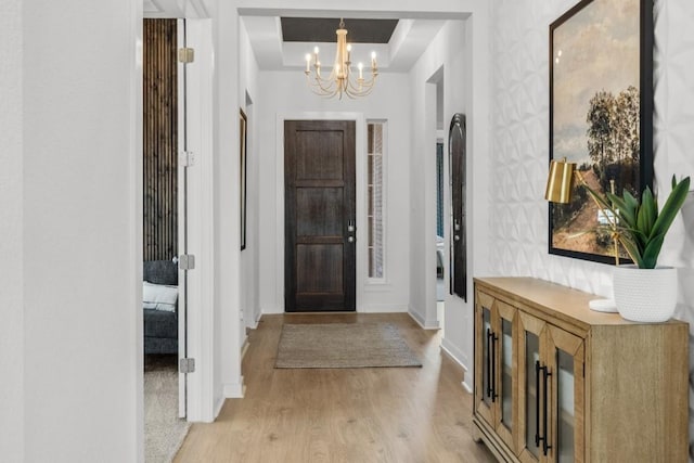 13615 Thomas Wheeler Way, Manor, TX 78653 - entrance foyer featuring a chandelier, light wood-style flooring, baseboards, and a raised ceiling
