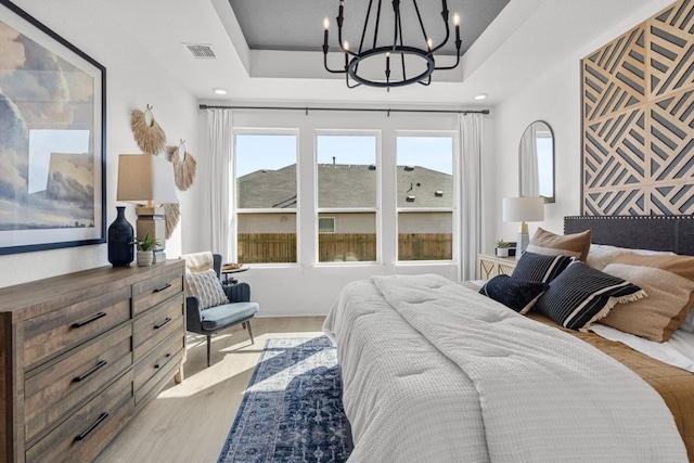 13615 Thomas Wheeler Way, Manor, TX 78653 - bedroom featuring a tray ceiling, a chandelier, and wood finished floors