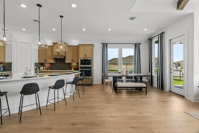 13615 Thomas Wheeler Way, Manor, TX 78653 - kitchen featuring stainless steel appliances, a breakfast bar area, backsplash, light wood-style flooring, and recessed lighting