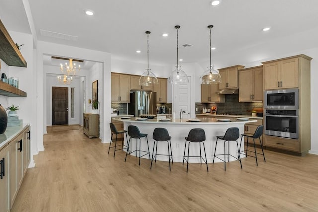 13615 Thomas Wheeler Way, Manor, TX 78653 - kitchen with stainless steel appliances, under cabinet range hood, a breakfast bar area, decorative backsplash, and recessed lighting