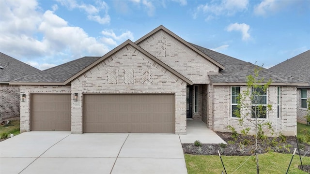 13504 Thomas Wheeler Way, Manor, TX 78653 - french country style house featuring brick siding, an attached garage, concrete driveway, and a shingled roof
