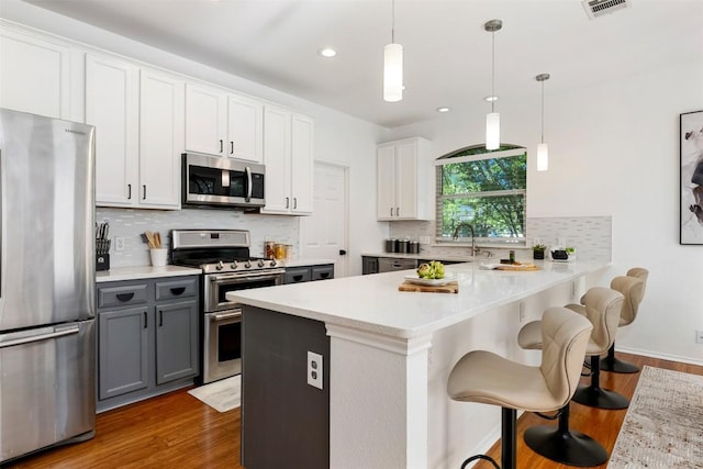 2126 Simbrah Dr, Cedar Park, TX 78613 - kitchen with stainless steel appliances, gray cabinets, wood finished floors, decorative backsplash, and recessed lighting