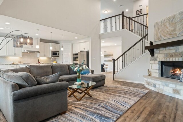 5621 Cypress Ranch Blvd, Spicewood, TX 78669 - living room featuring wood finished floors, a towering ceiling, stairs, a fireplace, and recessed lighting