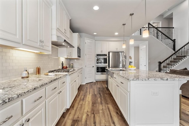5621 Cypress Ranch Blvd, Spicewood, TX 78669 - kitchen with appliances with stainless steel finishes, hardwood / wood-style floors, white cabinetry, tasteful backsplash, and light stone countertops