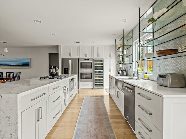 1004 Maufrais St, Austin, TX 78703 - kitchen featuring appliances with stainless steel finishes, beverage cooler, a kitchen island, white cabinets, and light wood-type flooring